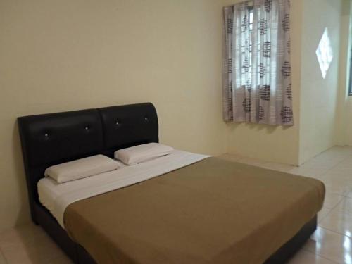 a bedroom with a bed with a black headboard and a window at Golden Hill Double Storey Homestay at Night Market in Cameron Highlands