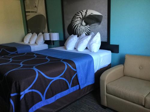 a hotel room with two beds and a chair at Super8 by Wyndham NEARBY Clearwater St Petersburg International Airport in Clearwater