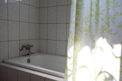y baño con bañera y cortina de ducha. en Alice Springs Homestay, en Tianfu