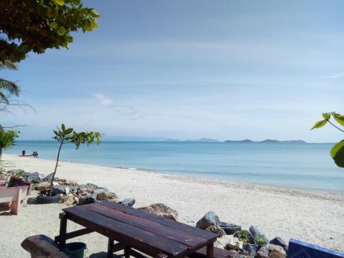 una panchina di legno seduta su una spiaggia con l'oceano di Thongsom Resort a Khanom