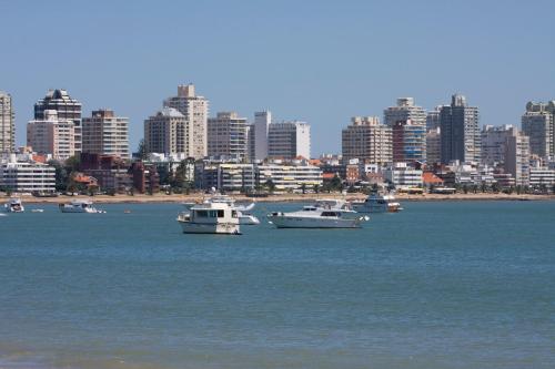 a group of boats in the water with a city at Hotel Sunset Beach in Punta del Este