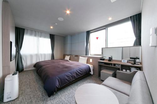 Sanco Inn Nagoya Shinkansen-guchi Annex في ناغويا: غرفه فندقيه بسرير واريكه
