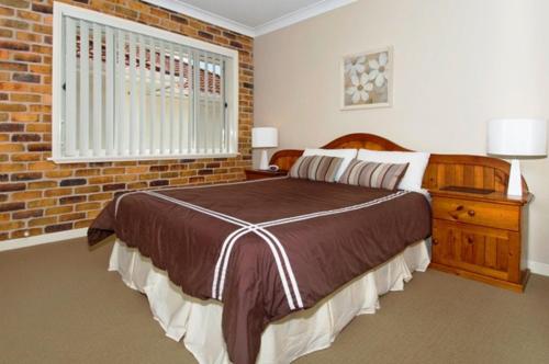 a bedroom with a bed and a brick wall at Mainsail 10 17 Owen Street in Port Macquarie