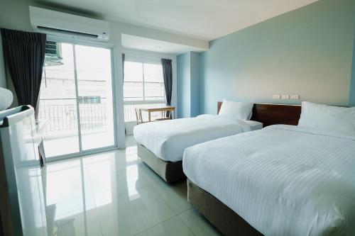 Una habitación de hotel con dos camas y una gran ventana. en Thongchen Residence, en Samut Sakhon