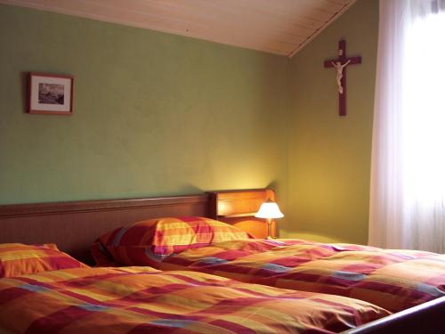 two beds in a bedroom with a cross on the wall at Ferienwohnung Patricia Schipper in Gemünden