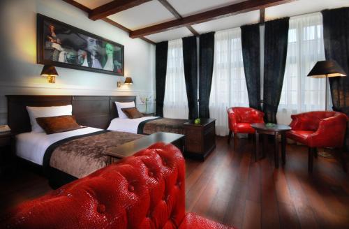 a hotel room with two beds and a red chair at Hotel Holland House Old Town in Gdańsk