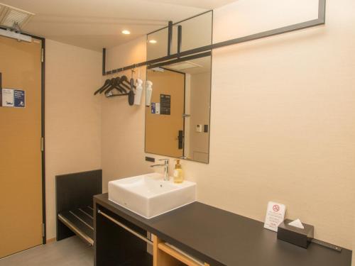 a bathroom with a sink and a mirror at HATAGO INN Kansai Airport in Izumi-Sano