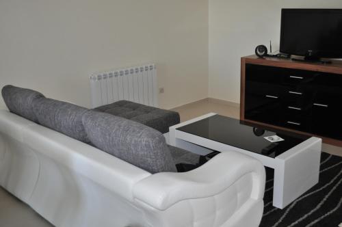 a living room with a white couch and a tv at Apartments Soleado in Pančevo