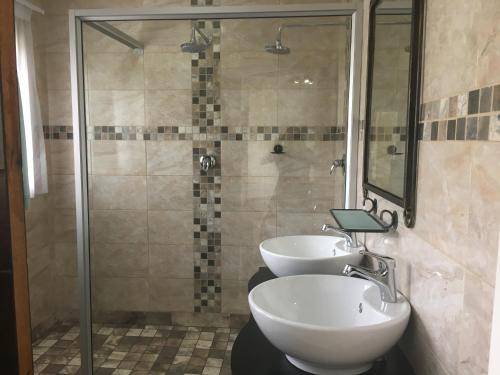 a bathroom with two sinks and a shower at Isle La Breeze Guest House in Witbank