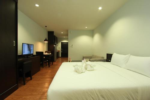 a bedroom with a large white bed and a living room at The Park 304 Executive Serviced Apartment in Si Maha Phot