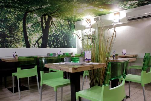 a restaurant with green chairs and tables and a mural at Atipik Hôtel in Annecy