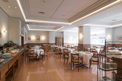 um restaurante com mesas e cadeiras num quarto em Hotel Blanca de Navarra em Pamplona