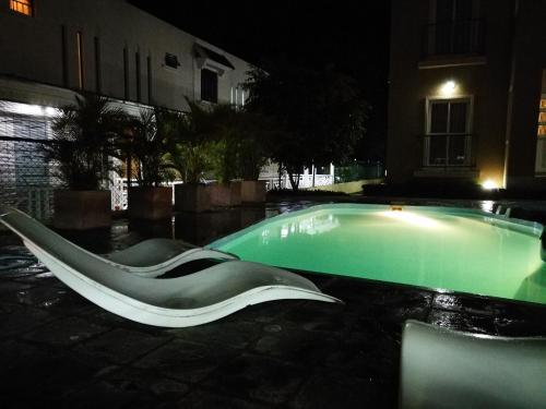Rayon Vert Bleuphorie Beach Apartment في فليك-إن-فلاك: مسبح في الليل مع زحليقة بجانب مبنى