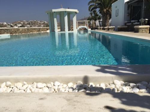 a swimming pool with blue water and rocks around it at Peristeronas Village in Klouvas