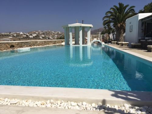 a large swimming pool with blue water and palm trees at Peristeronas Village in Klouvas
