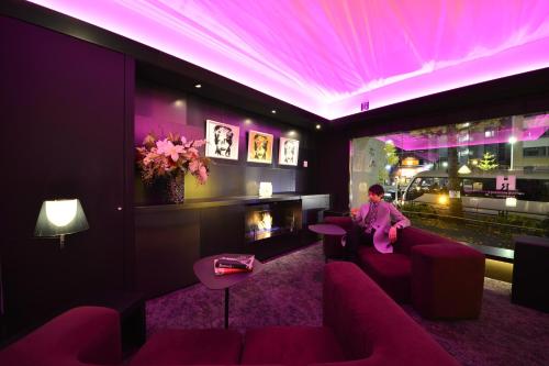 a woman sitting on a couch in a room with purple lighting at Roppongi Hotel S in Tokyo