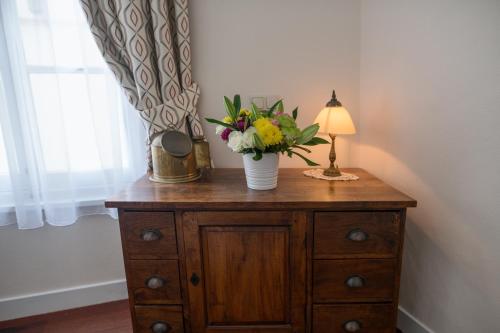 a vase of flowers on a dresser with a lamp at Keizershouse Amsterdam in Amsterdam