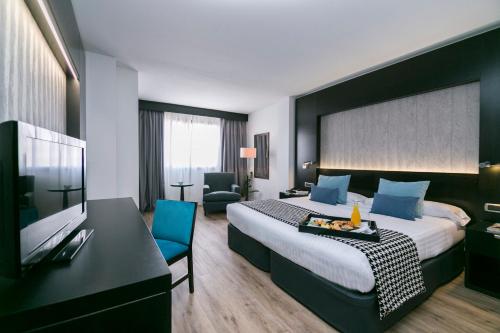 a hotel room with a king sized bed and a desk at Intelier Rosa in Castellón de la Plana