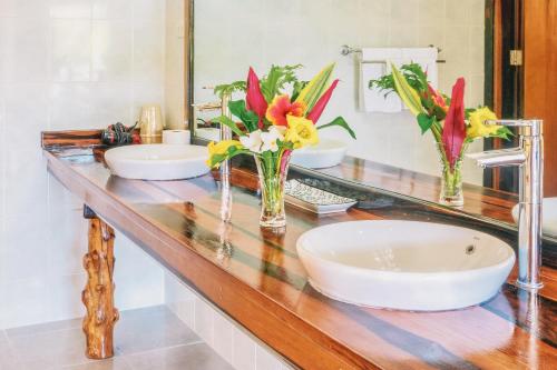 a bathroom with two sinks and flowers on a counter at Edgewater Dive & Spa Resort in Puerto Galera