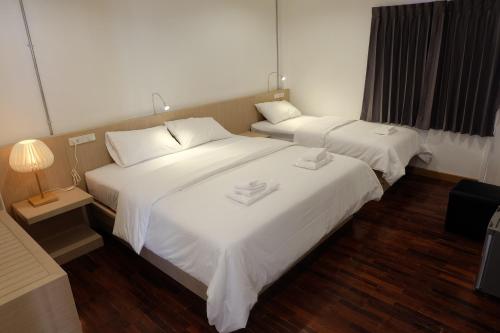 two beds in a hotel room with white sheets at F Plus F Hostel in Chiang Mai
