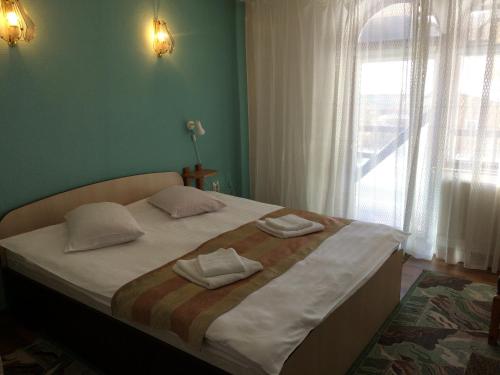 a bedroom with a large bed with two towels on it at Pension Casa Alba in Slănic-Moldova