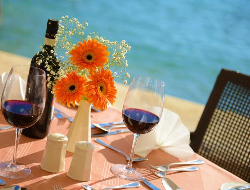 a table with two glasses of red wine and flowers at St. Patrick's Hotel in Xlendi
