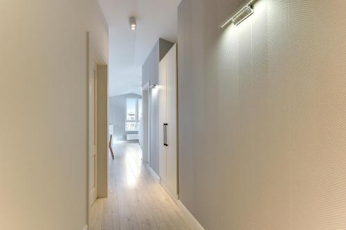 a hallway with a white wall and a door at Chrobry Apartamenty Gdańsk Grodzka 10 in Gdańsk