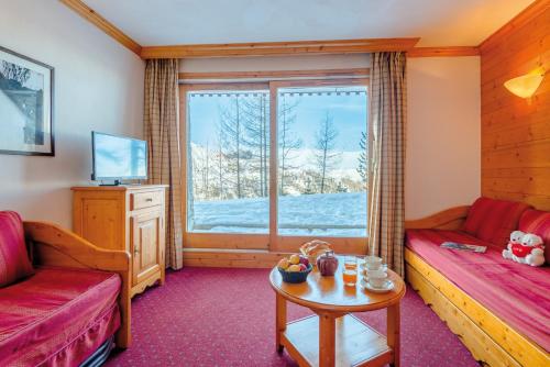 Mâcot La Plagneにあるtravelski home select - Résidence Aspen 4 étoilesのリビングルーム(ソファ、テーブル付)、窓が備わります。
