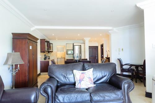 a leather couch in a living room with a kitchen at Ballito Manor Gardens 303 - With Generator in Ballito