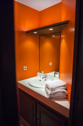 La salle de bains orange est pourvue d'un lavabo et d'un miroir. dans l'établissement The Originals City, Le Cottage Hôtel, Bruay-la-Buissière, à Bruay-la-Buissière