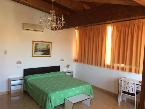 ein Schlafzimmer mit einem grünen Bett und einem Kronleuchter in der Unterkunft Hotel Aurora in Vieste