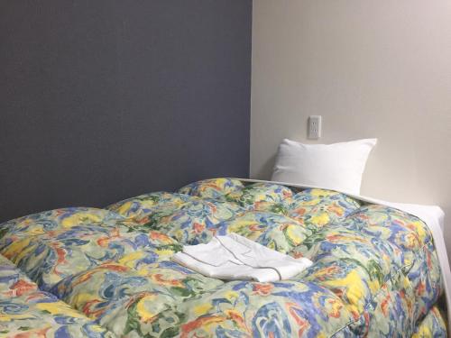 a pair of white shoes sitting on top of a bed at Hotel Todai in Mihara