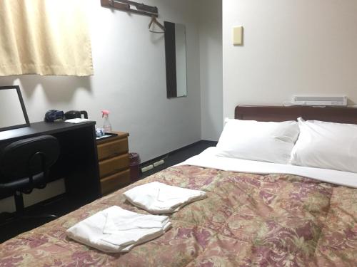 a bedroom with a bed with two towels on it at Hotel Todai in Mihara