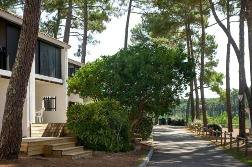 a house with a tree next to a sidewalk at VTF La Jaougue Soule in Biscarrosse-Plage