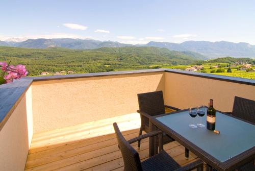a table with two glasses of wine on a balcony at Biobauernhof St. Quirinus in Caldaro