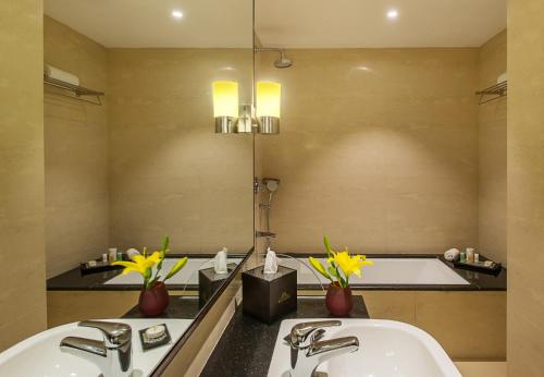 KK Royal Hotel & Convention Centre في جايبور: حمام مع مغسلتين وحوض استحمام