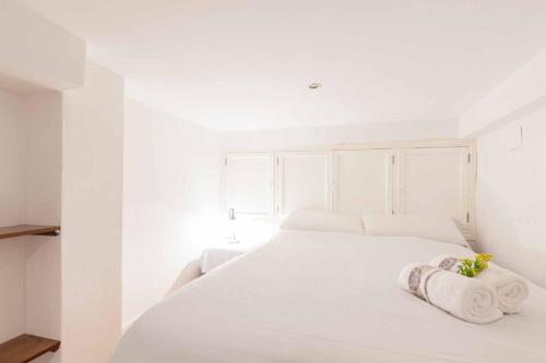 - une chambre blanche avec un lit blanc et des serviettes dans l'établissement Apartamento San Marco/Enladrillada, à Séville