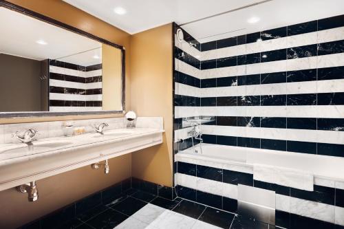 ein Badezimmer mit zwei Waschbecken, einer Badewanne und einem Spiegel in der Unterkunft Stallmästaregården Hotel, Stockholm, a Member of Design Hotels in Stockholm