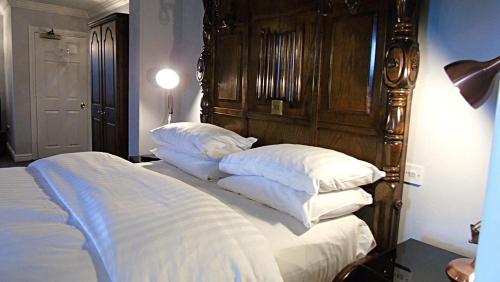 a bed with a wooden headboard and white pillows at The Lion Hotel in Belper