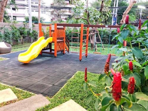 a playground with a yellow slide in a garden at Rain Cha-am Huahin By Sake in Cha Am