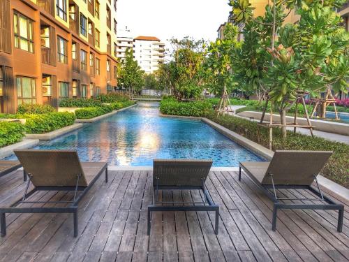 a pool in the middle of a building with two chairs at Rain Cha-am Huahin By Sake in Cha Am