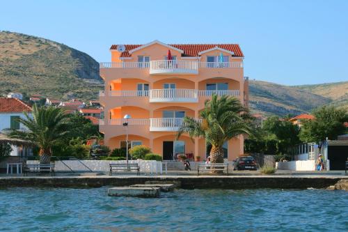 a large pink building next to a body of water at Kaja - right next to the beach in Trogir
