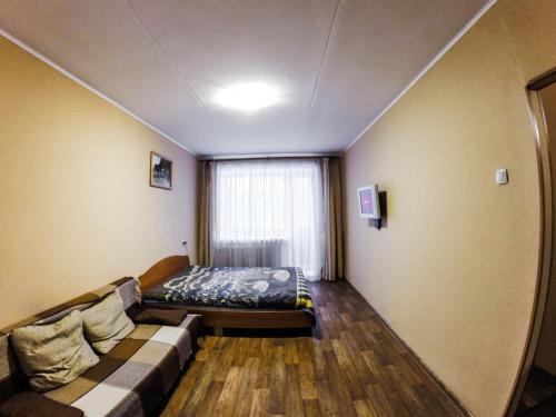 ペルミにあるApartments On Leninaのベッド1台、ソファ、窓が備わる客室です。