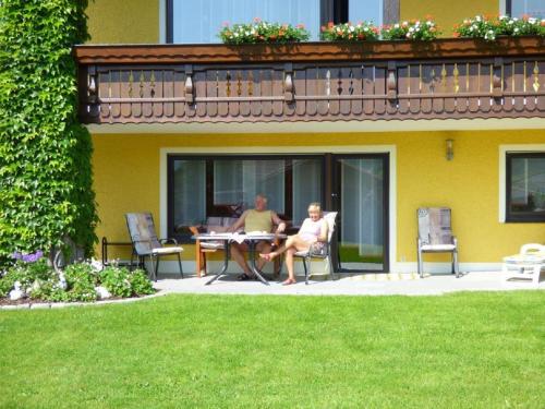 two people sitting at a table outside of a house at Landhaus Simon in Gleißenberg