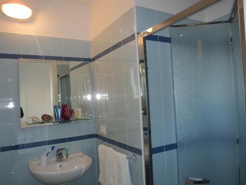 uma casa de banho com um lavatório e uma cabina de duche em vidro. em Hotel Irene em Riccione