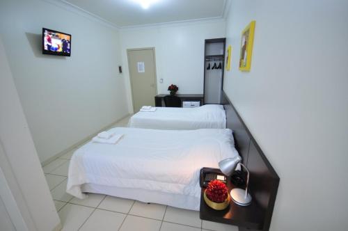 a bedroom with two beds with white sheets and fruit on a table at Hotel FIT in Palmas