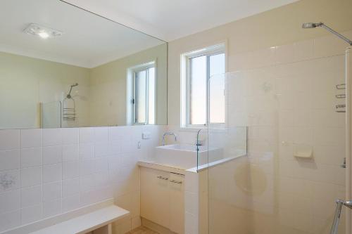 a bathroom with a sink and a shower and a mirror at Beach Breakers Apartment Stunning Views in Kianga