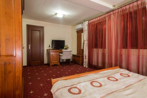 um quarto de hotel com uma cama, uma secretária e uma televisão em Red Hotel em Alexandria