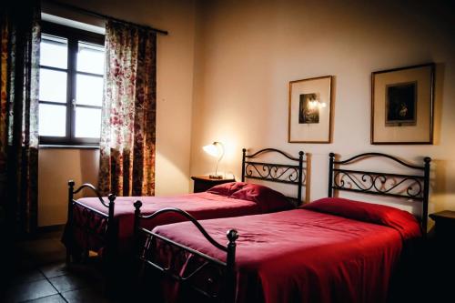 a bedroom with two beds with red sheets and a window at Sori San Giovanni in Isola d'Asti