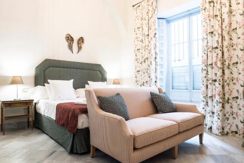 una camera con letto, divano e sedia di Palacio Mármoles a Siviglia